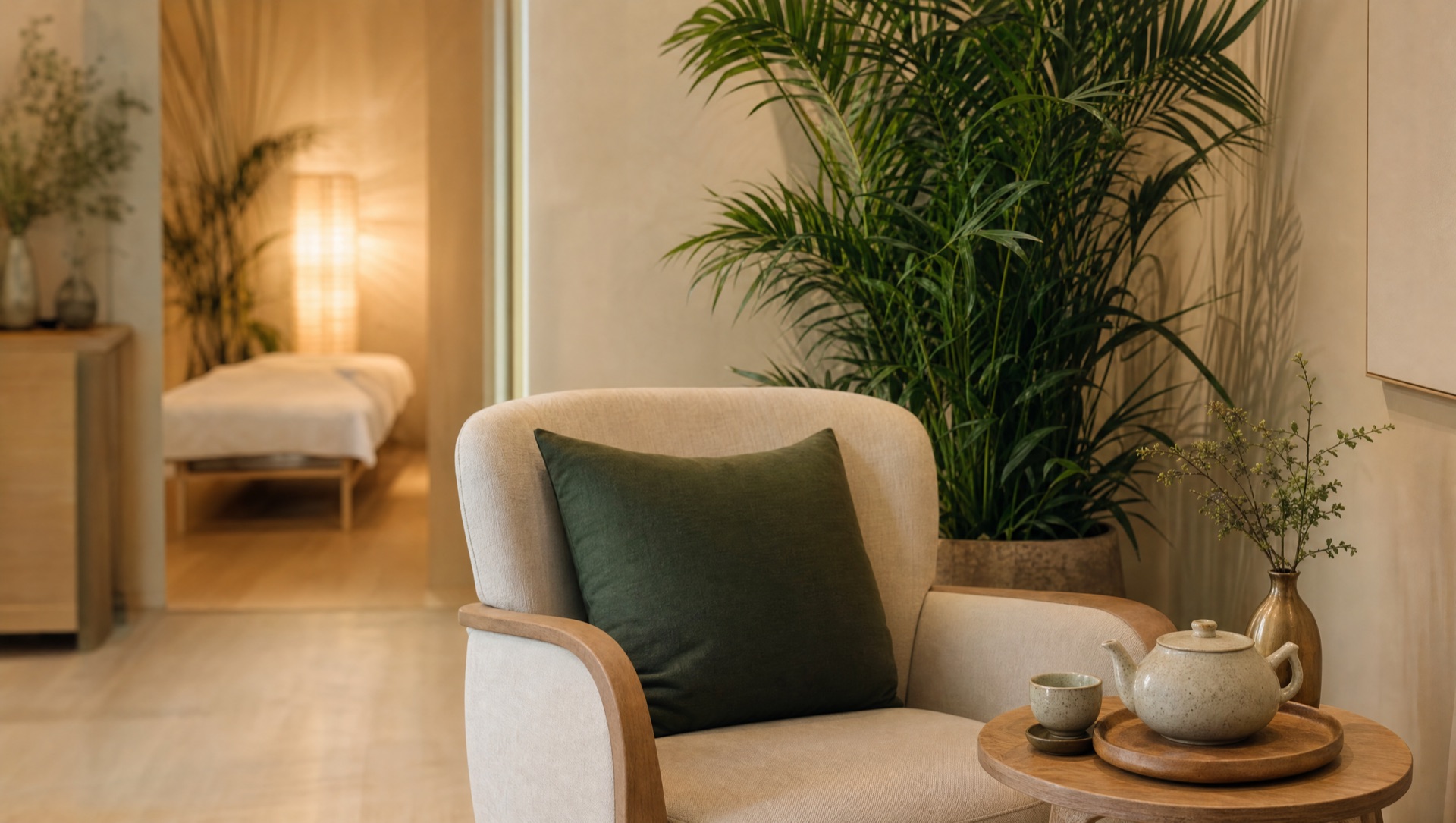 Calm studio reception corner with a linen armchair, potted plant, and ceramic tea set